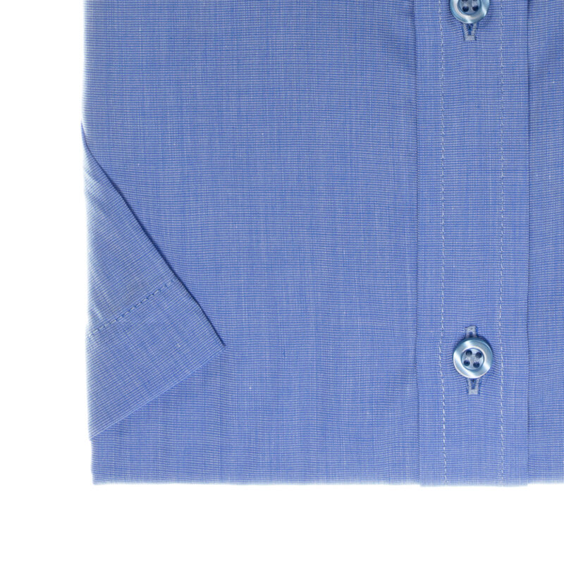 Detalhe da manga curta e peitilho da camisa azul lisa com botões.