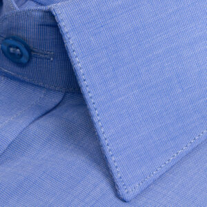 Textura do algodão azul liso com botão e costura reforçada em close.