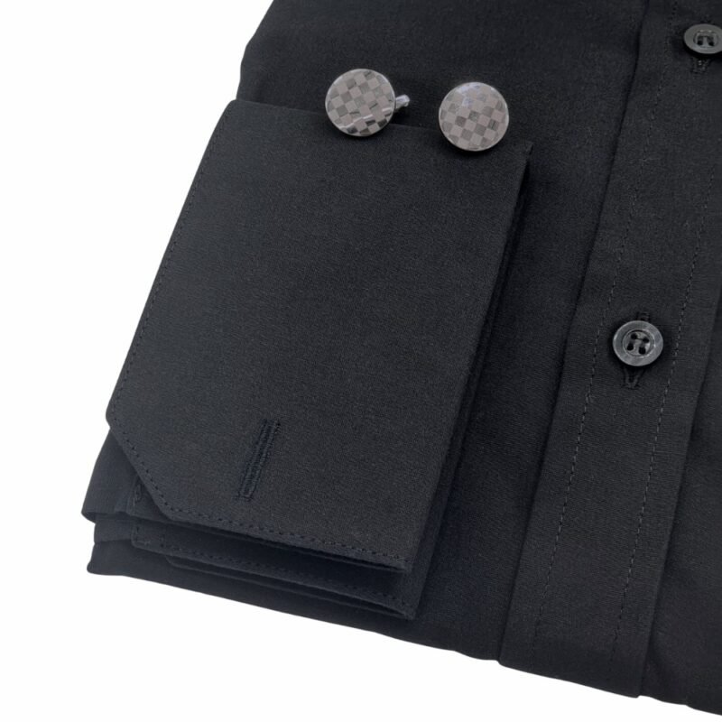 Close do punho da camisa preta lisa sulfite com abotoaduras metálicas de formato geométrico sobre o tecido.