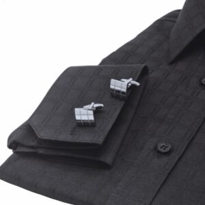 Close do punho duplo da camisa preta xadrez largo com abotoaduras geométricas em evidência.