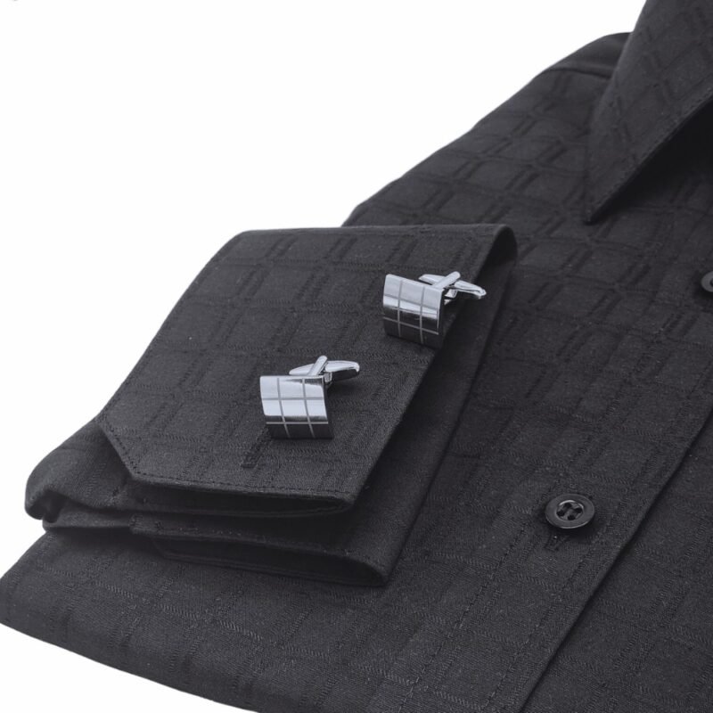 Close do punho duplo da camisa preta xadrez largo com abotoaduras geométricas em evidência.