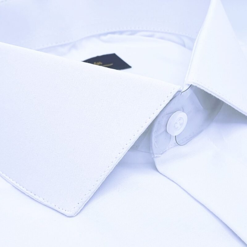 Detalhe da gola italiana branca lisa e do primeiro botão coberto da camisa, evidenciando o acabamento minimalista.