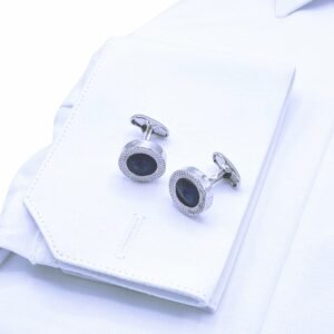 Close do punho duplo rígido da camisa italiana branca lisa com abotoaduras escuras em destaque.