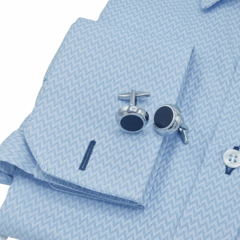 Camisa social azul clarinho maquinetada da Ms Stilos dobrada em posição diagonal, mostrando gola estruturada e punho duplo com abotoaduras sobre a peça.