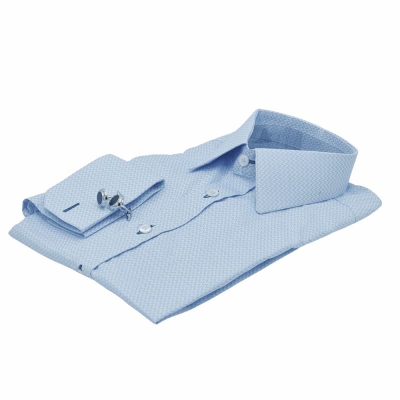 Close do punho duplo da camisa azul clarinho maquinetada da Ms Stilos com duas abotoaduras redondas prateadas, destacando a textura maquinetada do tecido.