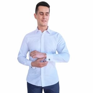 Modelo veste camisa branca lisa francesa em tecido passa fácil e ajusta o punho duplo, reforçando a proposta de elegância no dia a dia.