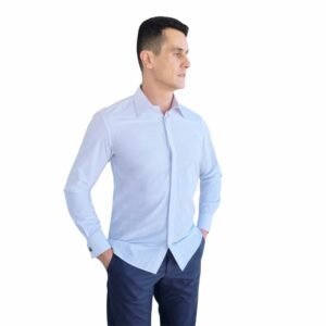 Modelo veste camisa branca lisa francesa com punho duplo em vista lateral, evidenciando caimento ajustado e linha limpa do tecido passa fácil.