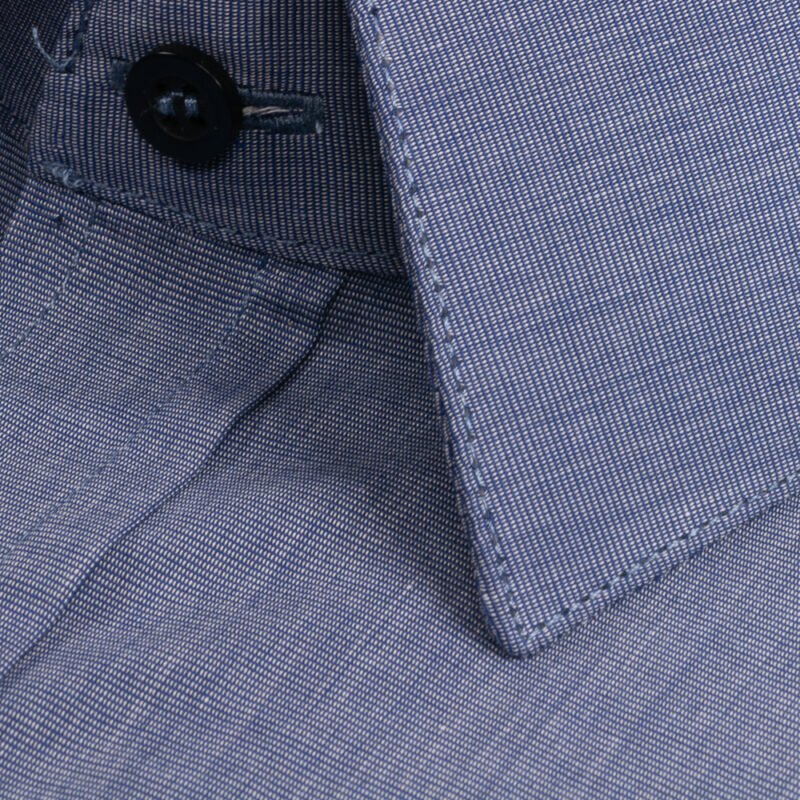 Close do tecido da camisa azul 100% algodão francesa e da gola, mostrando textura fina, elegância e qualidade premium.