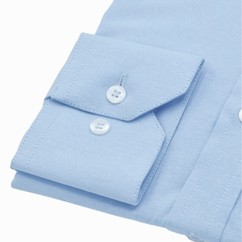 Close do punho da camisa azul lisa sulfite com botões reguláveis e costuras de alfaiataria em destaque.