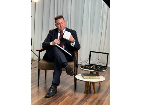 Samuel da MS Stilos analisando tecidos e opções de estilo durante a mentoria, sentado em ambiente sofisticado com amostras ao lado, representando atenção e expertise em imagem profissional.