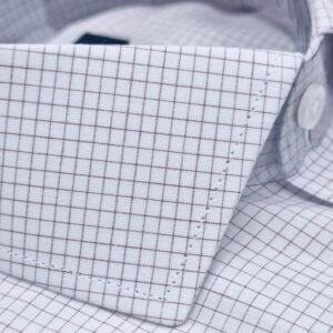 Close da textura do tecido quadriculado branco e bordô da camisa italiana fio egípcio, mostrando a trama discreta e o caimento suave na região da gola.