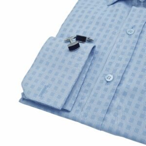 Detalhe do punho duplo da camisa social azul italiana xadrez dobrada, com par de abotoaduras metálicas em destaque sobre o punho