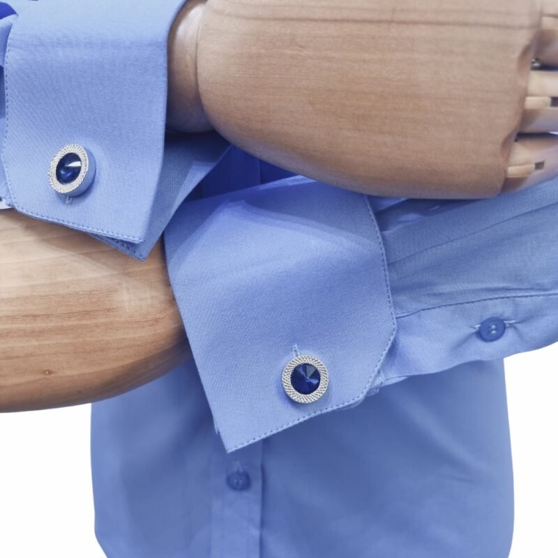 Detalhe dos punhos duplos da camisa italiana azul lisa em tecido sulfite, com abotoaduras metálicas nos punhos do manequim