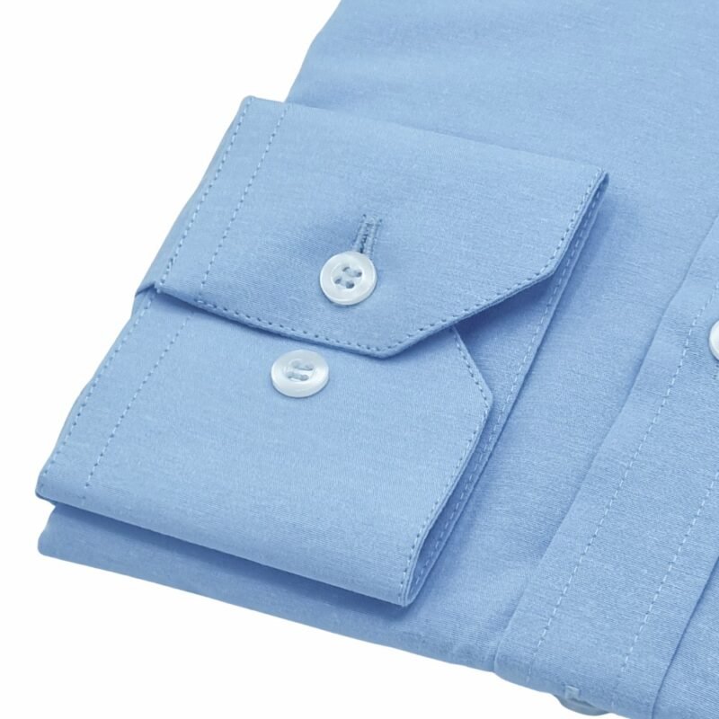 Detalhe do punho com botão regulável da camisa azul clarinho lisa sulfite, realçando acabamento.