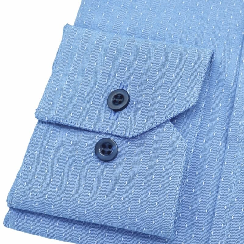 Detalhe em close do punho da camisa azul francesa 100% algodão com botões e regulagem, mostrando a textura do tecido.