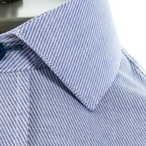 Close da gola italiana da camisa azul em algodão, evidenciando a textura do tecido e o acabamento da costura.
