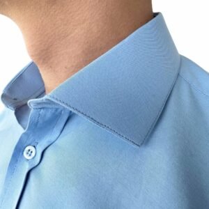Detalhe da gola italiana rígida da camisa azul lisa sulfite, emoldurando o pescoço com elegância.