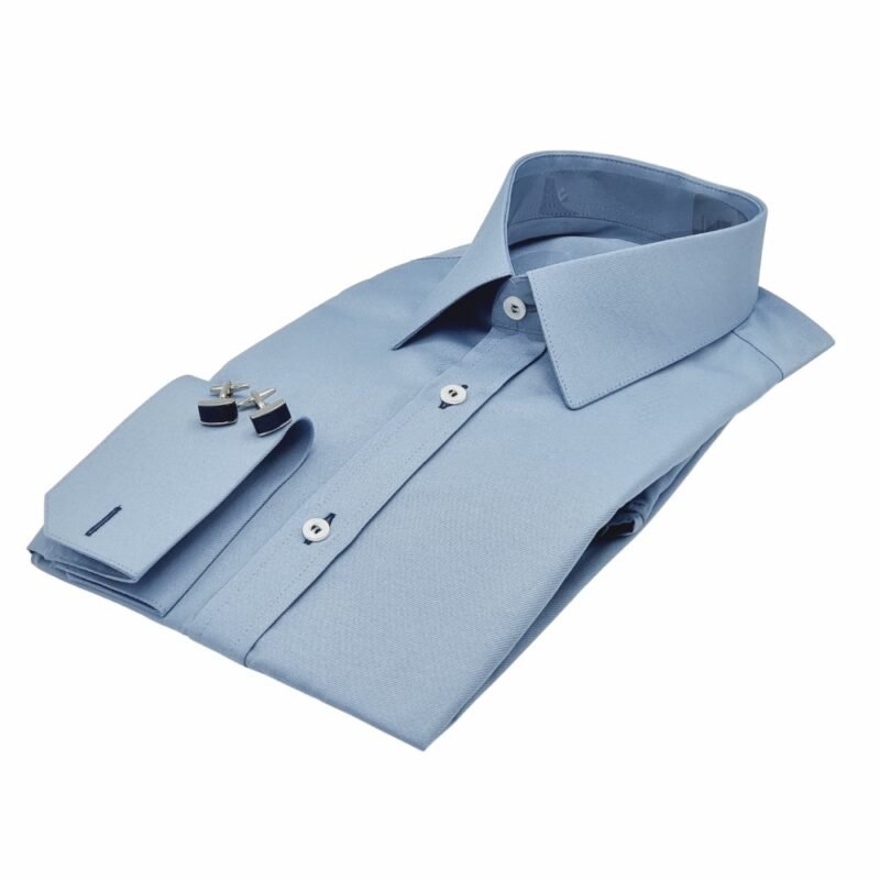 Camisa social azul maquinetado francesa com punho duplo e abotoaduras posicionadas sobre o punho, dobrada em perspectiva sobre fundo branco.