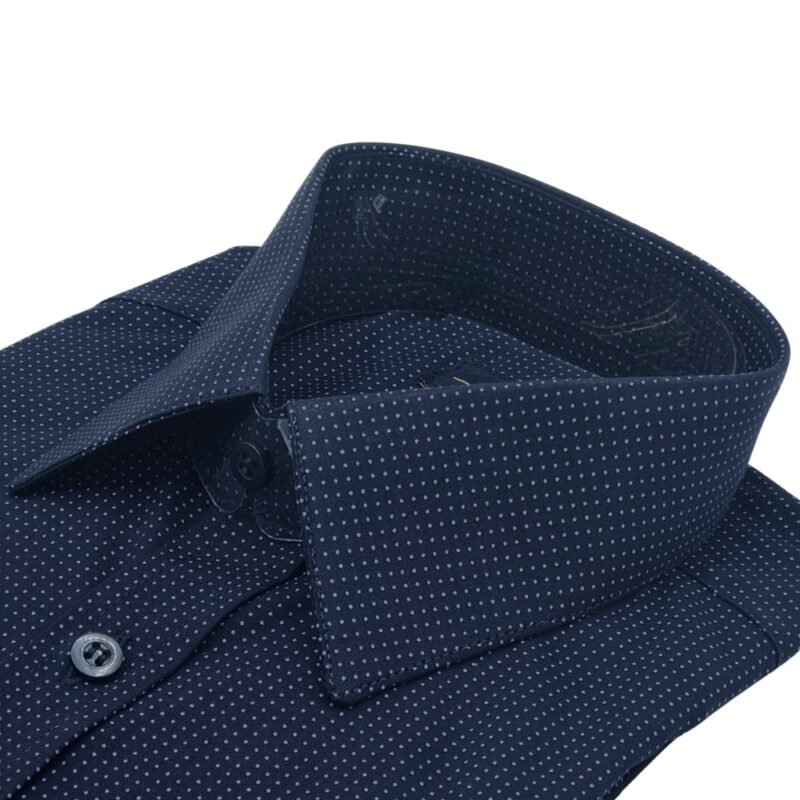Close lateral da gola francesa da camisa azul marinho com estampa de poá azul claro em destaque.