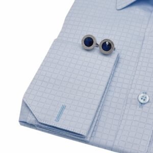 Detalhe do punho duplo da camisa egípcio azul clarinho em algodão premium, com par de abotoaduras metálicas azuis em destaque sobre o tecido maquinetado