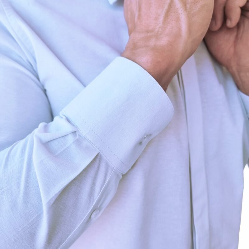 Close do punho da camisa francesa branca lisa sulfite, mostrando botão, costuras precisas e estrutura alongada da manga.