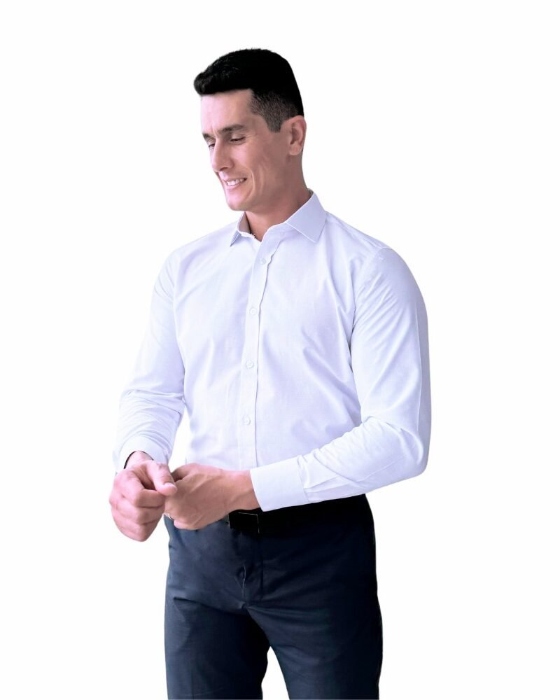 Modelo veste camisa italiana branca lisa sulfite semi slim de frente, ajustando o punho em fundo claro.