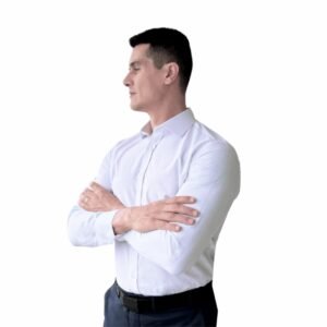 Modelo usa camisa italiana branca lisa sulfite semi slim em meio perfil, destacando ombros e peitoral.