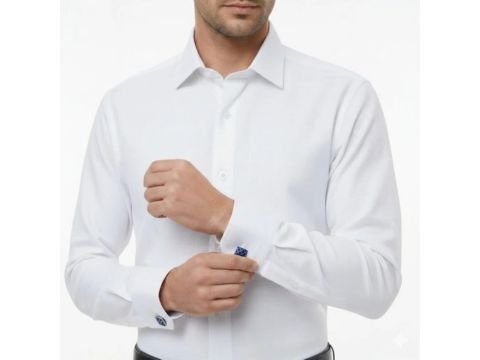 Homem usando camisa italiana branca da MS Stilos, ajustando o punho duplo com abotoaduras azuis em fundo claro