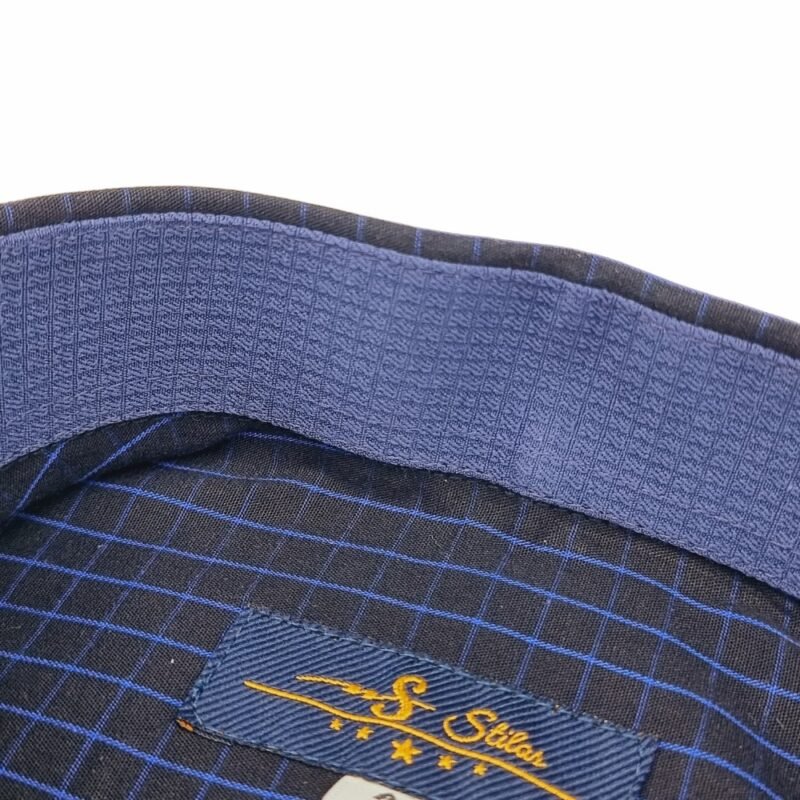 Detalhe da parte interna da gola da camisa preta xadrez azul, com tecido azul texturizado e etiqueta da Ms Stilos em destaque.
