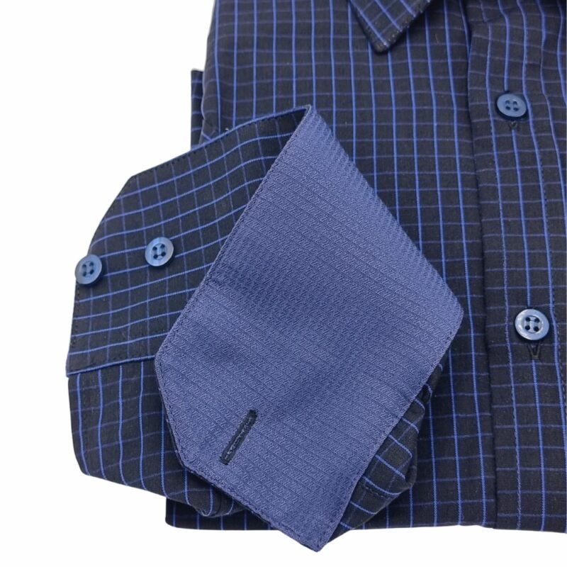 Punho da camisa preta xadrez azul virado para cima, revelando a parte interna em tecido azul texturizado com botões alinhados.