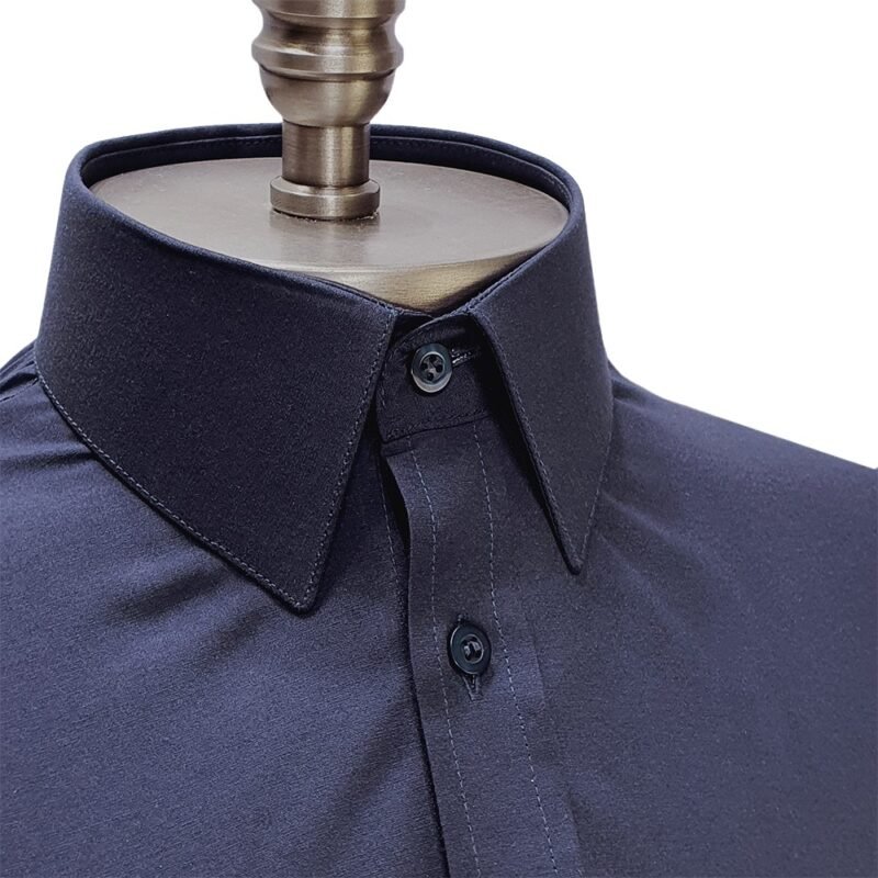 Close da gola francesa estruturada da camisa social azul marinho lisa, com peitilho e botões frontais em destaque.