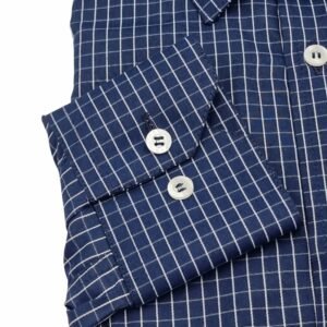Close do punho com botões da camisa social azul xadrez branco evidenciando o acabamento e o padrão xadrez.