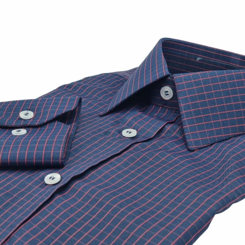 Close na frente da camisa social azul xadrez vermelho com punho dobrado e botões claros em evidência.