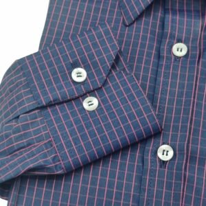 Close no punho de botão da camisa social azul xadrez vermelho mostrando o padrão xadrez e os botões claros.