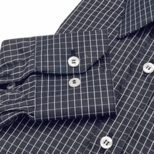 Close do punho com botões da camisa social preta xadrez branco evidenciando o acabamento e o padrão xadrez do tecido.