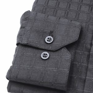 Close do punho com botões da camisa social preta com padronagem xadrez larga, destacando a textura do tecido.