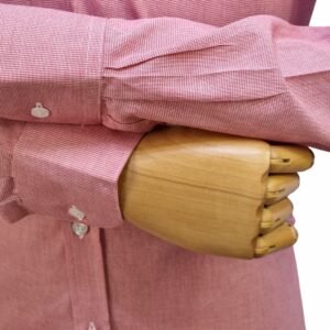 Close no punho com botão e manga cruzada da camisa social vermelha 100% algodão sobre mão de manequim de madeira.