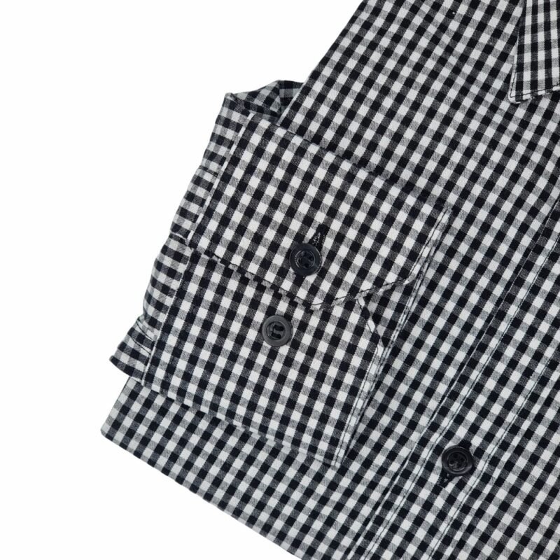 Detalhe do punho da camisa xadrez preta e cinza 100% algodão, com botões escuros alinhados e acabamento de alfaiataria.