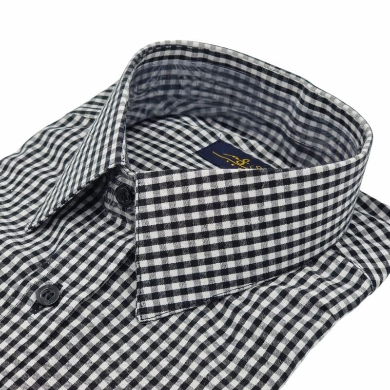 Camisa social xadrez preta e cinza em algodão 100%, dobrada em vista frontal completa com gola e punho à mostra sobre fundo branco.