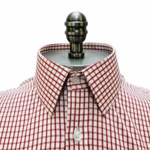 Close frontal na gola francesa estruturada da camisa xadrez vermelho em algodão passa fácil com botões claros alinhados.