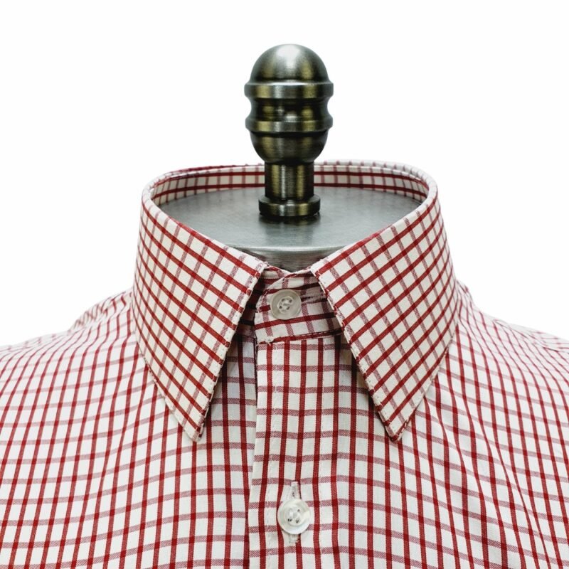 Close frontal na gola francesa estruturada da camisa xadrez vermelho em algodão passa fácil com botões claros alinhados.