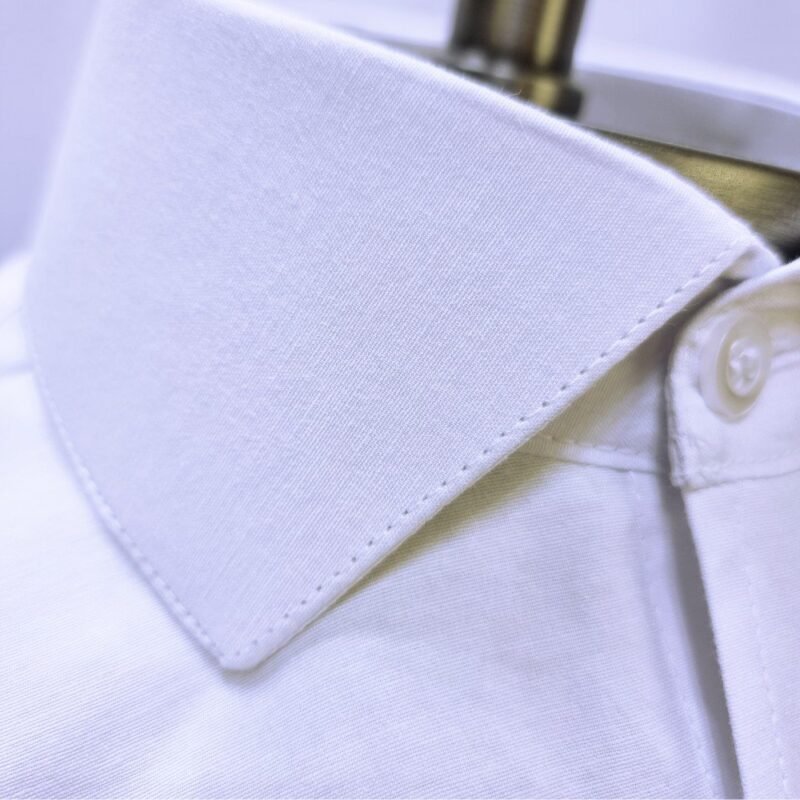 Macro da textura do tecido sulfite e ponta do colarinho italiano em camisa branca no manequim - MS Stilos.