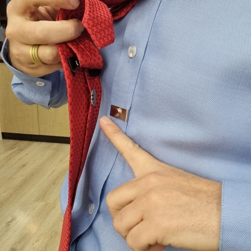 Detalhe aproximado da base magnetica do ima fixada no tecido da camisa social azul
