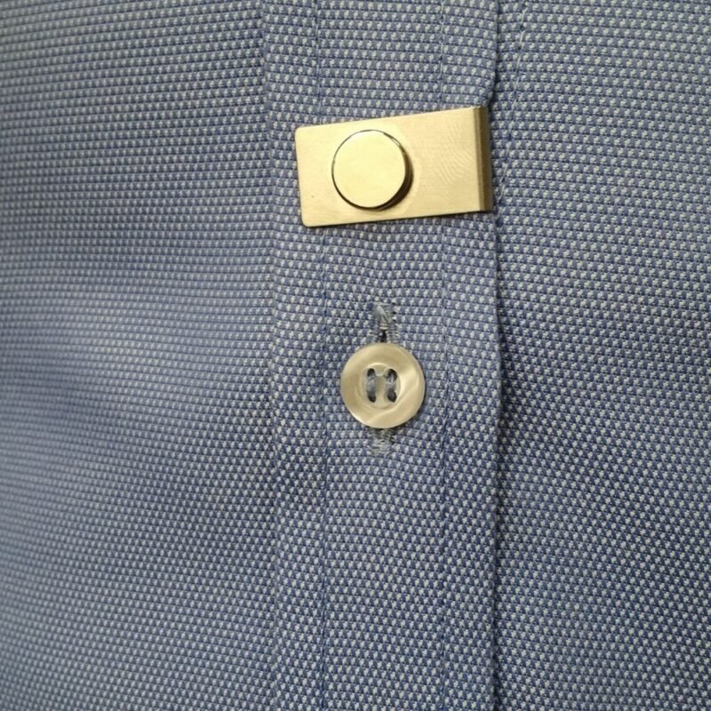 Homem demonstrando o ponto de fixacao do ima magnetico na camisa social indicando com o dedo a posicao do acessorio