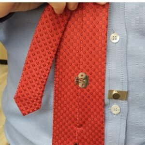 Ima magnetico para gravata instalado na camisa social azul mantendo a gravata vermelha fixa na posicao correta