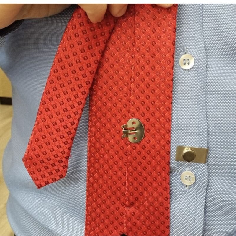Ima magnetico para gravata instalado na camisa social azul mantendo a gravata vermelha fixa na posicao correta
