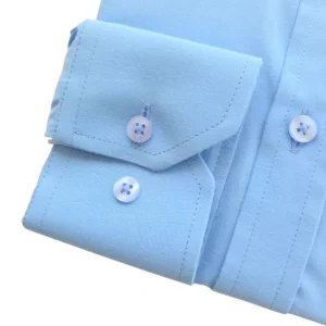 Detalhe do punho de botão da camisa azul lisa, com o pesponto da borda