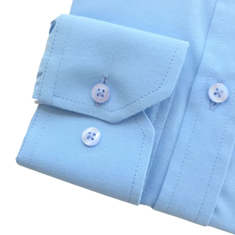 Detalhe do punho de botão da camisa azul lisa, com o pesponto da borda