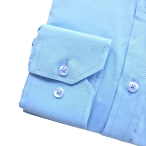 Detalhe do punho de botão da camisa social azul lisa em tecido passa fácil