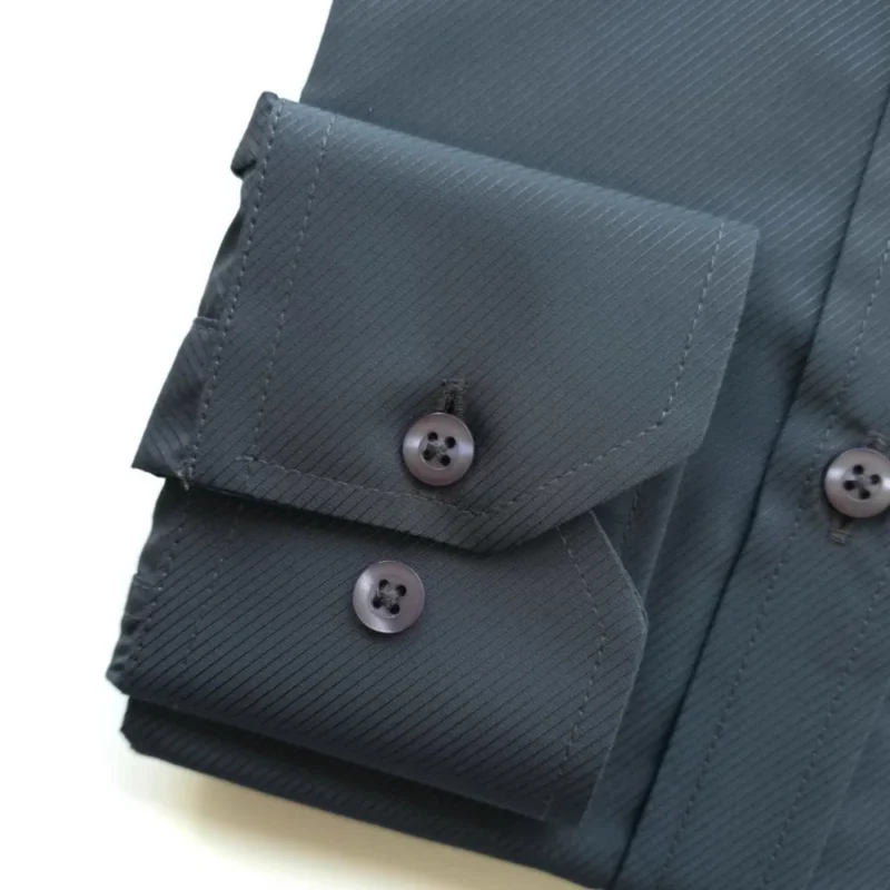 Detalhe do punho de botão da camisa cinza chumbo, com o relevo do tecido maquinetado